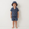 Child wearing a navy patterned outfit with a matching hat on a white background