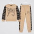 A two-piece kids' sweatshirt and jogger set in beige and black, hanging on white hangers against a white background. The sweatshirt features a beige body with black patterned sleeves and a large 'Boy' graphic on the chest.