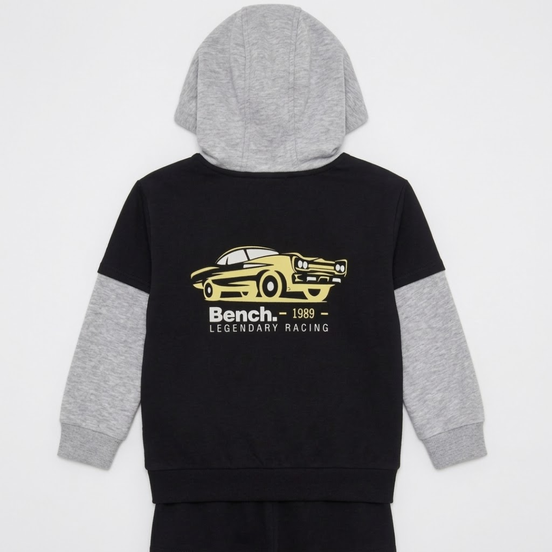 A kids' hooded sweatshirt shown from the back, featuring a black body, heather gray sleeves and hood, and a yellow graphic of a race car with the text 'Bench. 1989.
