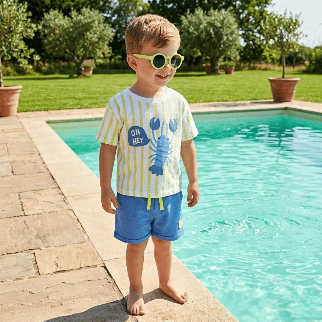 Child wearing sunglasses and a striped shirt by a pool