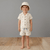 Child wearing a matching shirt and shorts set with a hat on a wooden floor.
