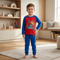 Young boy standing in a modern, brightly lit room wearing a red and blue Spider-Man long-sleeve pajama set with one hand on his hip.