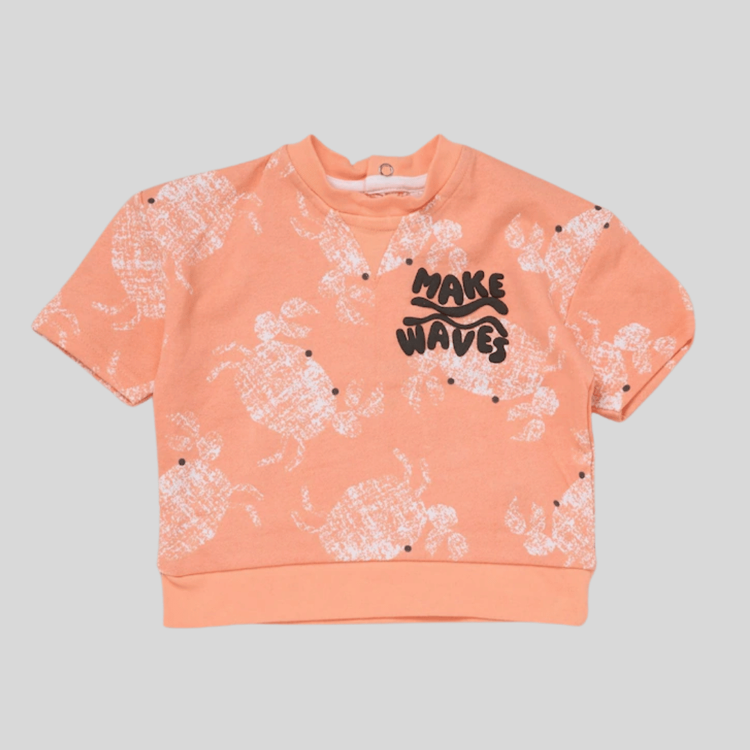 Peach-colored sweatshirt with white patterns and 'MAKE WAVES' text on a gray background
