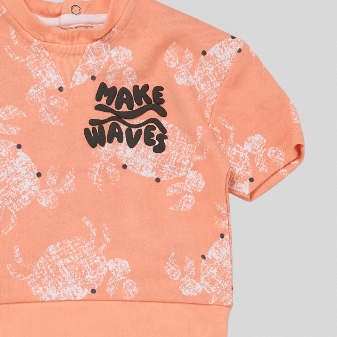 Peach-colored sweatshirt with white abstract patterns and black 'MAKE WAVES' text on a light gray background