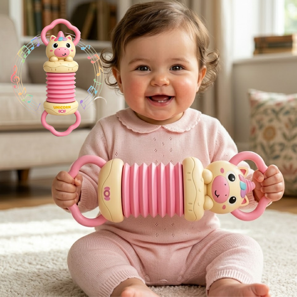 Baby in pink outfit holding a toy with a smiling expression, with another toy in the background.
