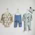 Set of baby clothing with Mickey Mouse design in hangers on a light gray background