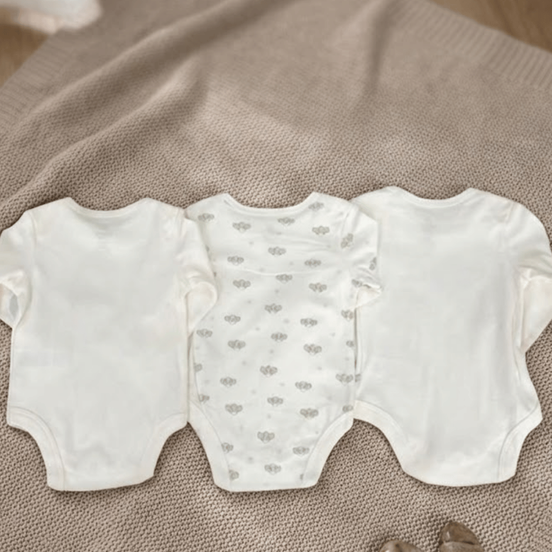 Three baby rompers on a textured surface
