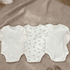 Three baby rompers on a textured surface