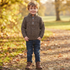 Boys autumn cable-knit half-zip jumper and denim jeans outfit, modeled outdoors in a fall setting.