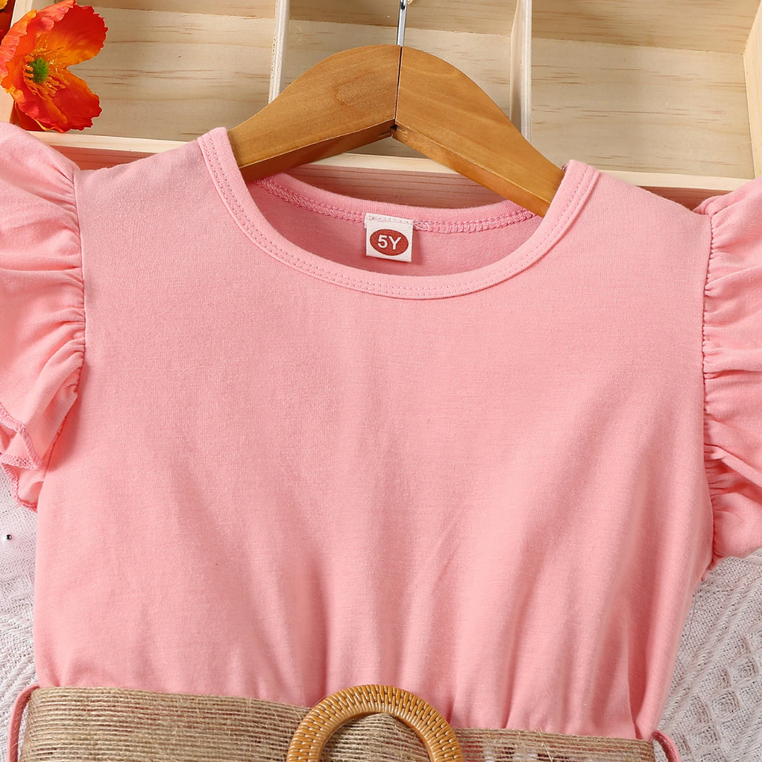 Pink children's top on a wooden hanger with a floral background