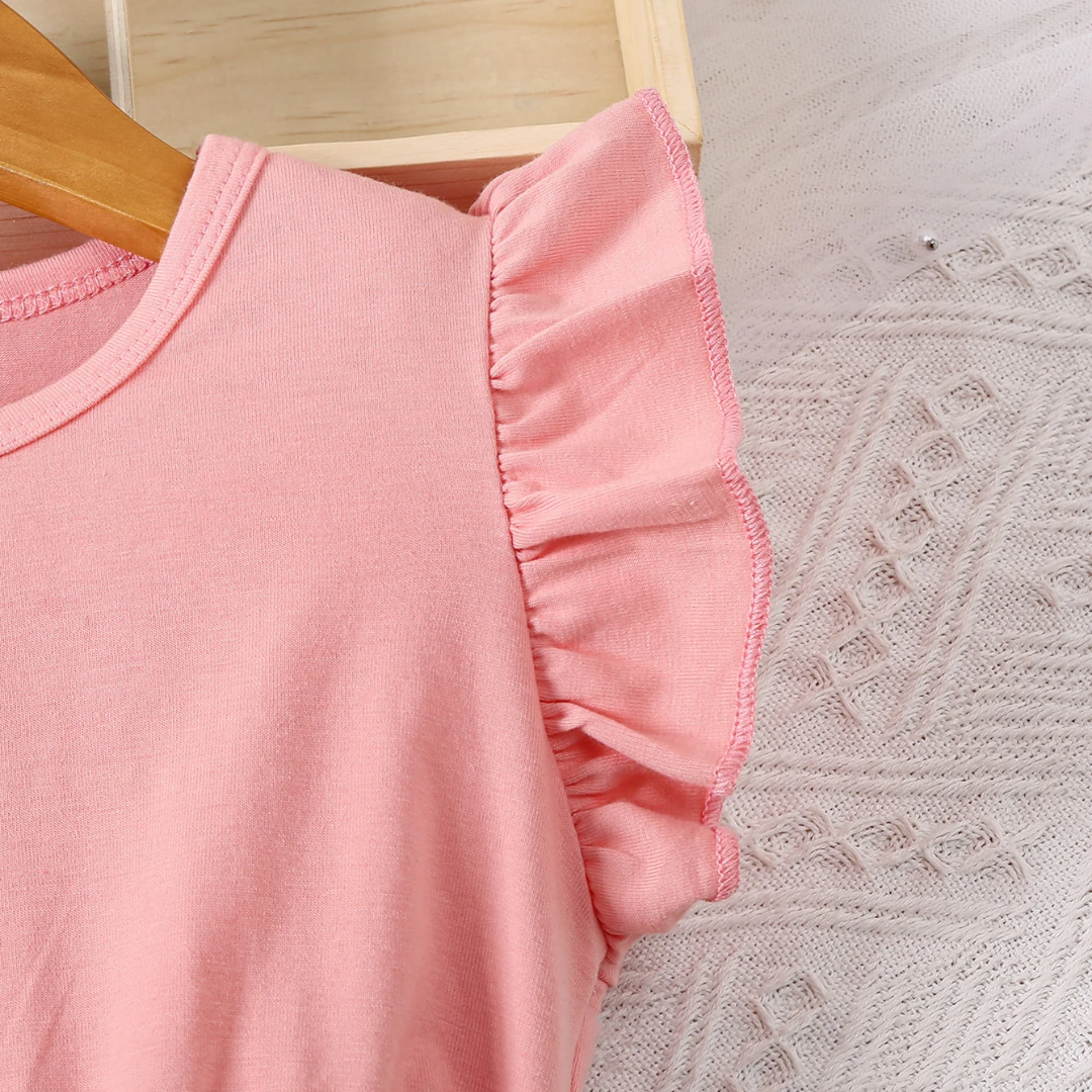 Pink ruffled dress on a wooden hanger with a textured surface background