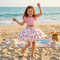 Young girl in a floral dress on a beach with ocean in the background