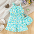 Children's turquoise romper with floral pattern on a wooden surface