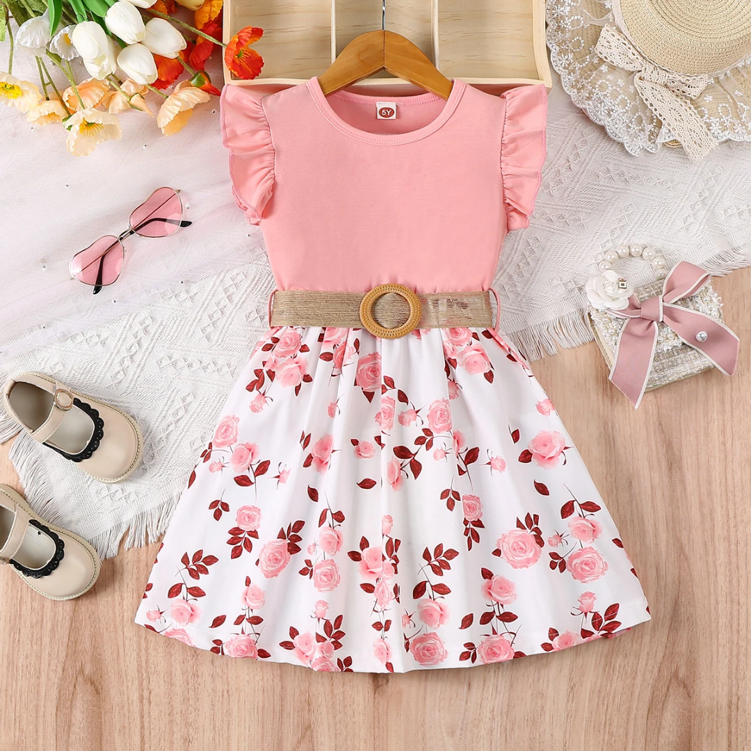 Pink dress with floral skirt on a wooden surface with accessories around