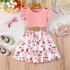 Pink dress with floral skirt on a wooden surface with accessories around
