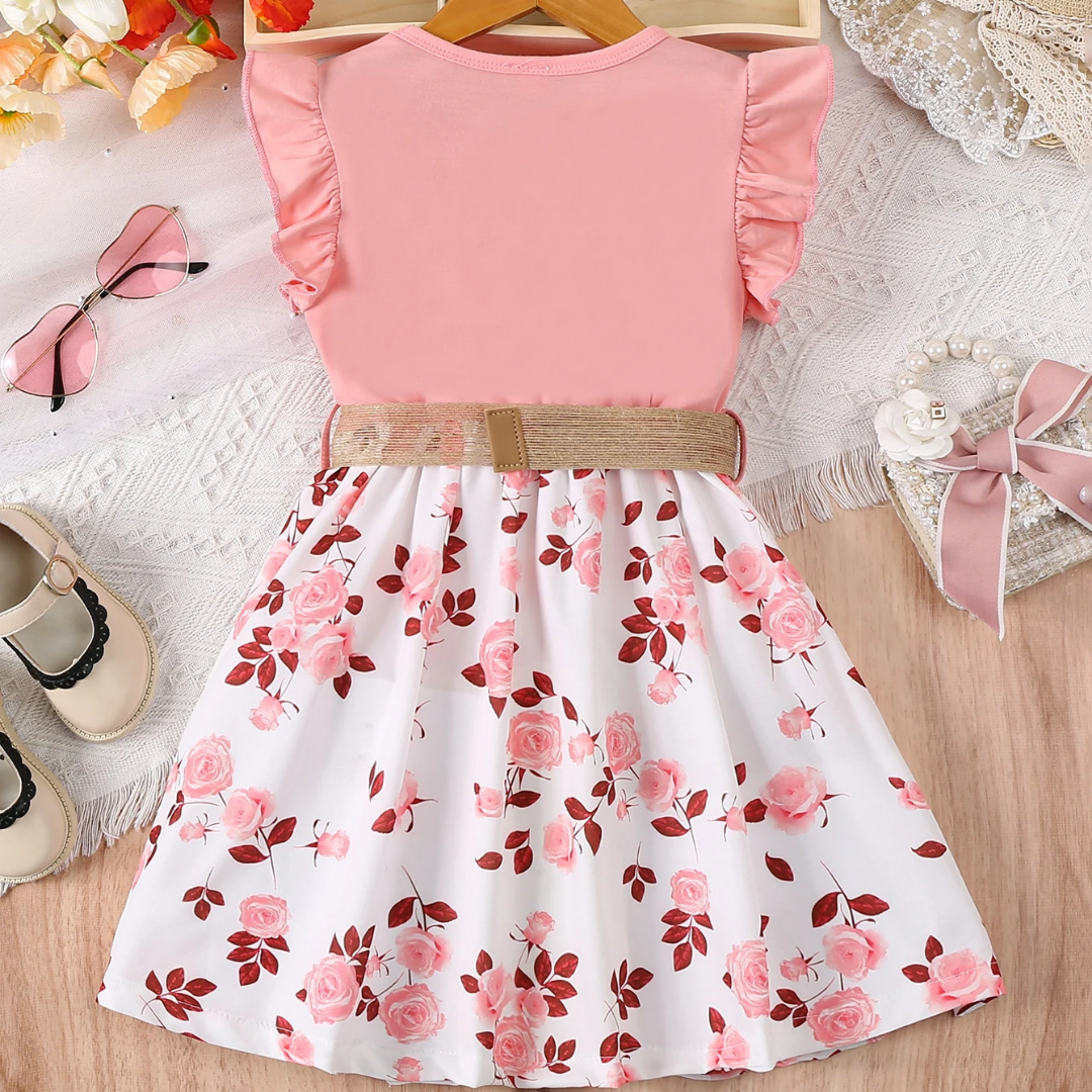 Pink top and floral skirt dress on a wooden surface with shoes and lace in the background.