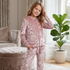 Smiling young girl posing in a brightly lit room wearing a dusty pink crushed velour zip-up hoodie and jogger pants set.   