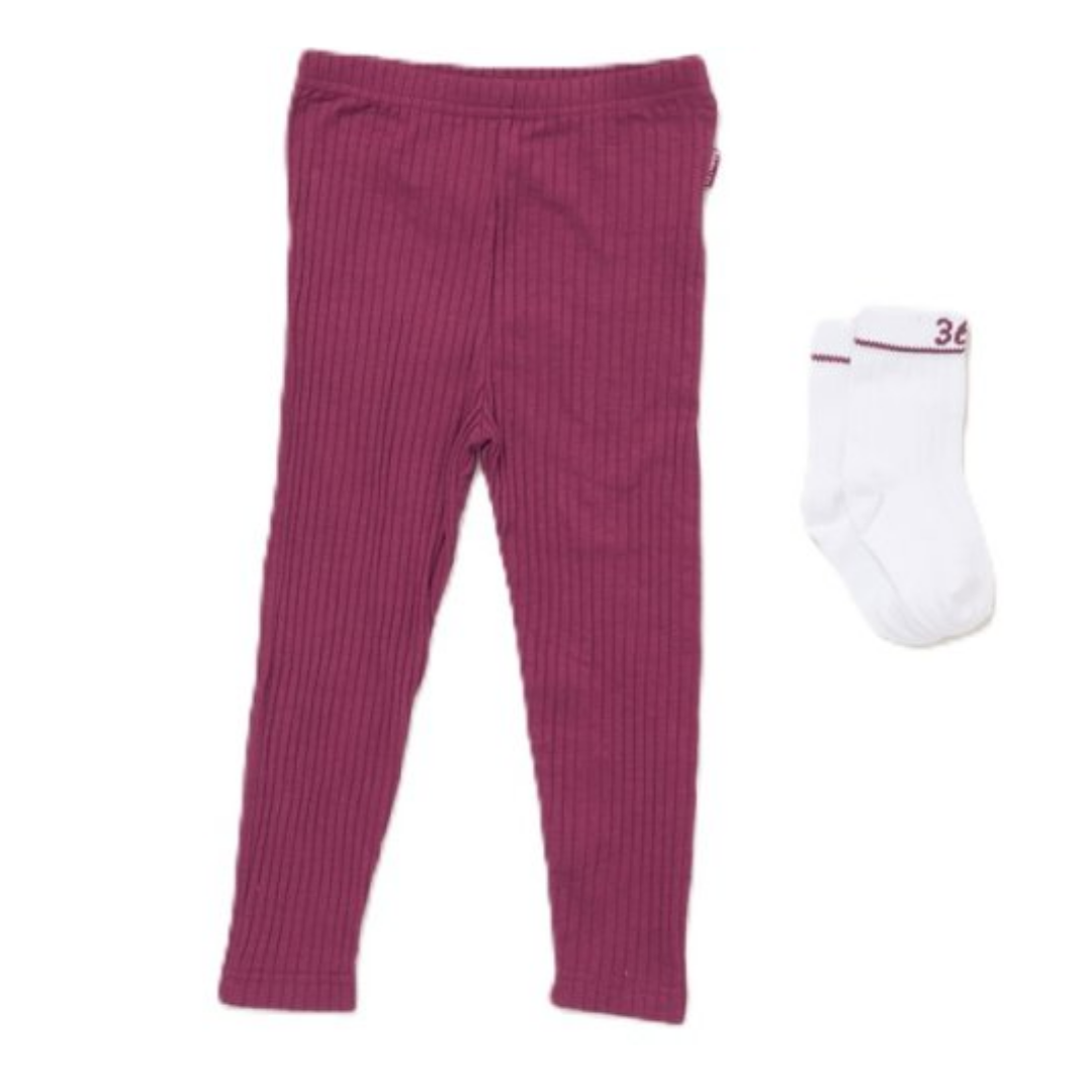 A pair of toddler ribbed leggings in a deep magenta pink, shown next to a pair of white baby socks with a red stripe and the number 36, on a plain white background.