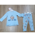 A children's two-piece outfit set laid flat on a wooden floor, featuring a light blue long-sleeve top with a teddy bear graphic and matching light blue leggings with a teddy bear print.