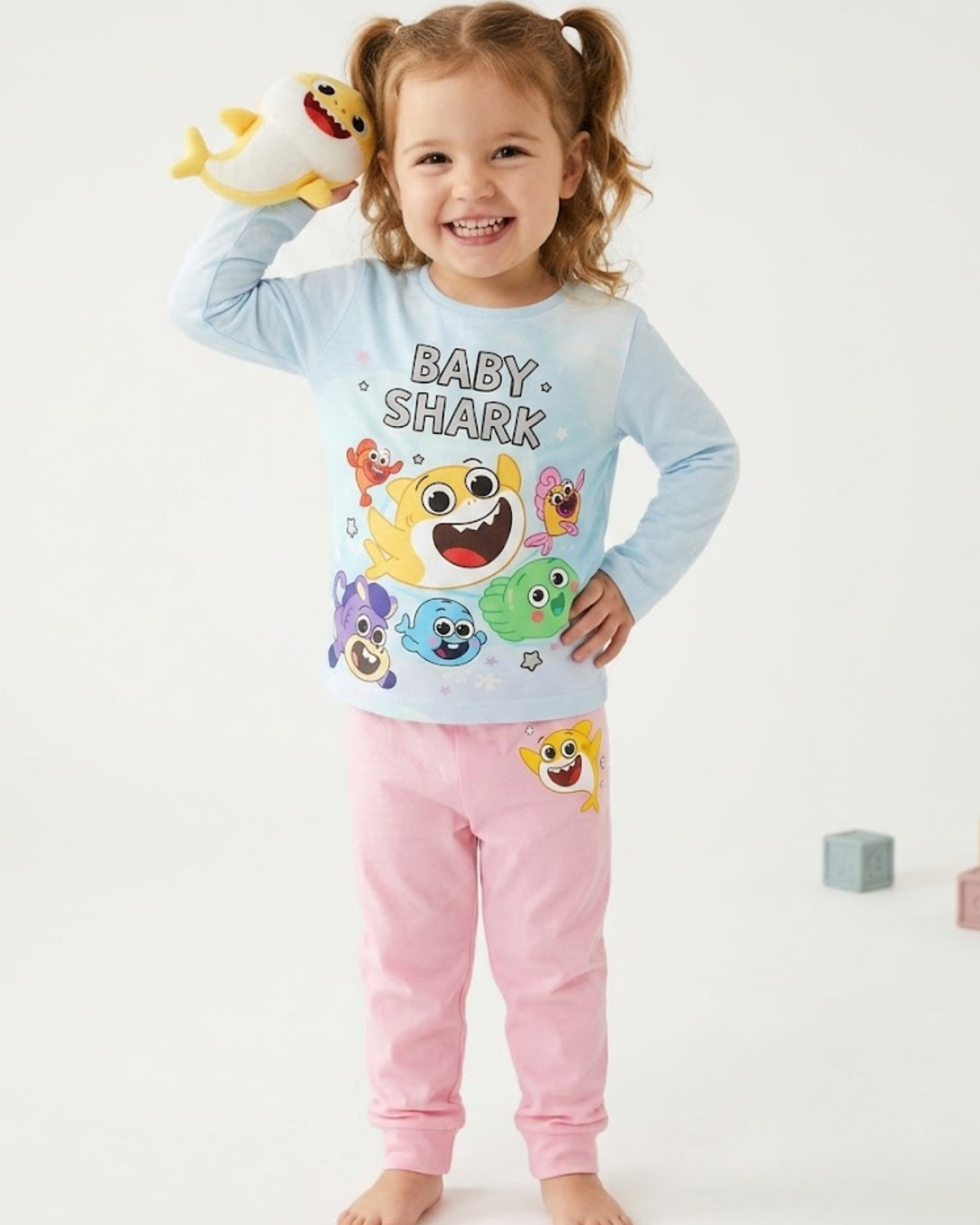 Child wearing a 'Baby Shark' themed pajama set on a white background