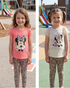 Two children wearing Minnie Mouse-themed clothing outdoors with playground equipment in the background.