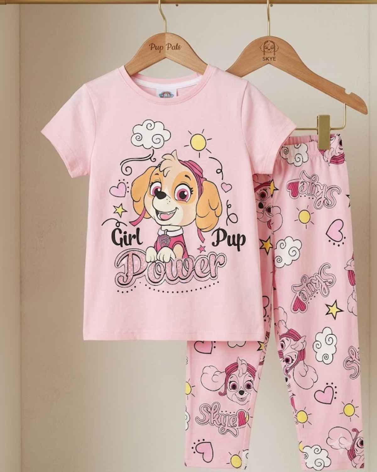 Pink children's pajama set with cartoon character and 'Girl Pup Power' text on a beige background.