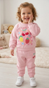 Child wearing a pink outfit with colorful graphics in a cozy room.