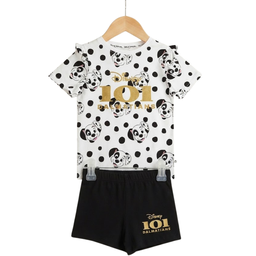A children's two-piece outfit on a wooden hanger, featuring a white short-sleeve top with black polka dots, Dalmatian face prints, and a gold 'Disney 101 Dalmatians' logo, paired with black shorts with a matching gold logo.