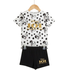 A children's two-piece outfit on a wooden hanger, featuring a white short-sleeve top with black polka dots, Dalmatian face prints, and a gold 'Disney 101 Dalmatians' logo, paired with black shorts with a matching gold logo.