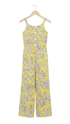 A yellow sleeveless jumpsuit with a gray palm leaf and white floral pattern, hanging on a wooden hanger against a white background.