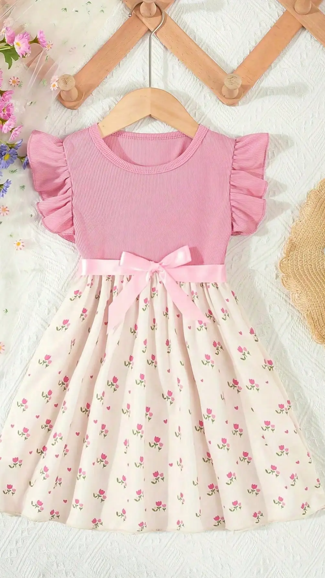 Pink dress with floral pattern on a hanger against a light background
