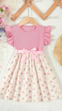 Pink dress with floral pattern on a hanger against a light background