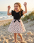 Child in a black top and floral skirt on a beach