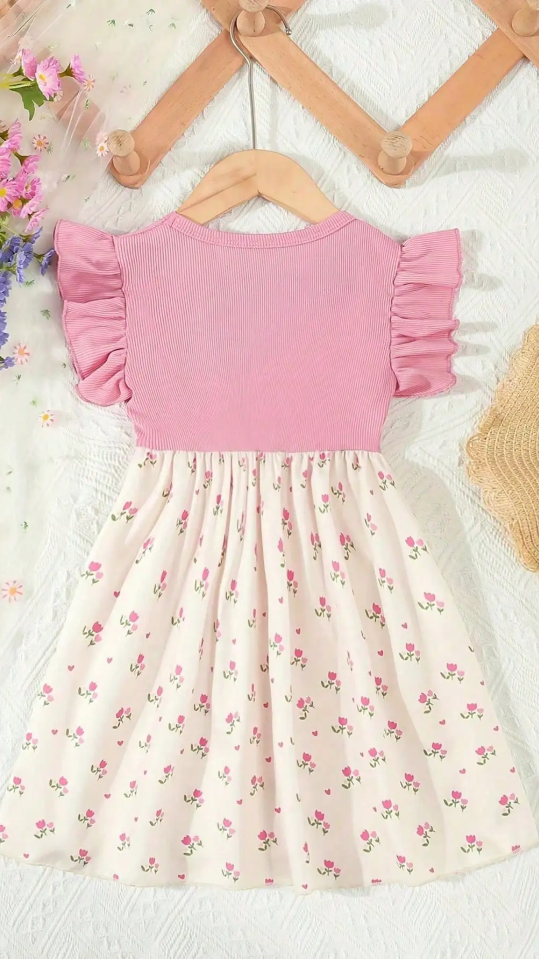 Pink top and floral skirt set on a white background with flowers and a hat.