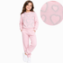 A young girl modeling a light pink two-piece sweatpants set with silver glittery heart patterns, shown against a plain white background with a circular detail inset of the heart pattern.