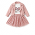 A toddler girl's outfit set featuring a light pink faux-leather moto jacket, a white graphic t-shirt with a pink sequin bow, a matching pink sequined tutu skirt, and a pair of cream ankle boots, laid out on a white background.