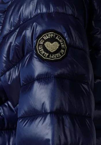 Blue puffer jacket with a gold heart-shaped patch on a dark background