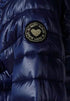 Blue puffer jacket with a gold heart-shaped patch on a dark background