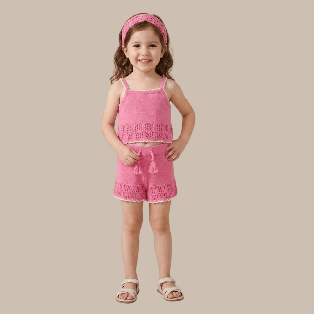 Young girl wearing a pink crochet outfit with a matching headband on a beige background