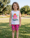 Young girl wearing a sleeveless top with a pineapple design and shorts in a park.