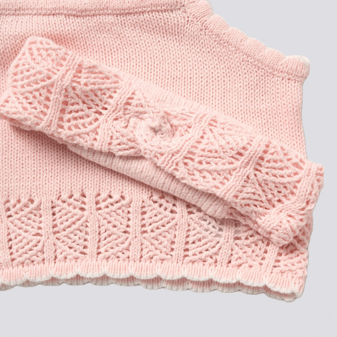 Pink knitted scarf with a textured pattern on a light gray background