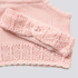 Pink knitted scarf with a textured pattern on a light gray background