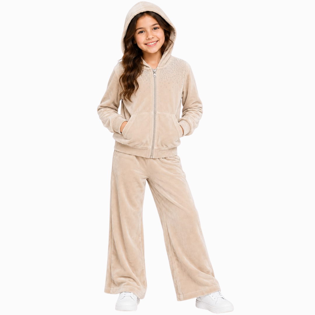 A young girl modeling a matching beige fleece zip-up hoodie and wide-leg sweatpants set against a plain white background.