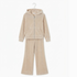 A two-piece children's loungewear set in a soft beige velour fabric, featuring a zip-up hooded sweatshirt and matching wide-leg pants, hanging on a metal hanger against a plain white background.