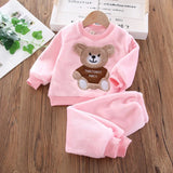 Pink children's outfit with bear design on a wooden surface