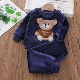 Navy blue children's outfit with teddy bear design on a wooden surface
