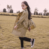 Child wearing a beige trench coat in an outdoor setting