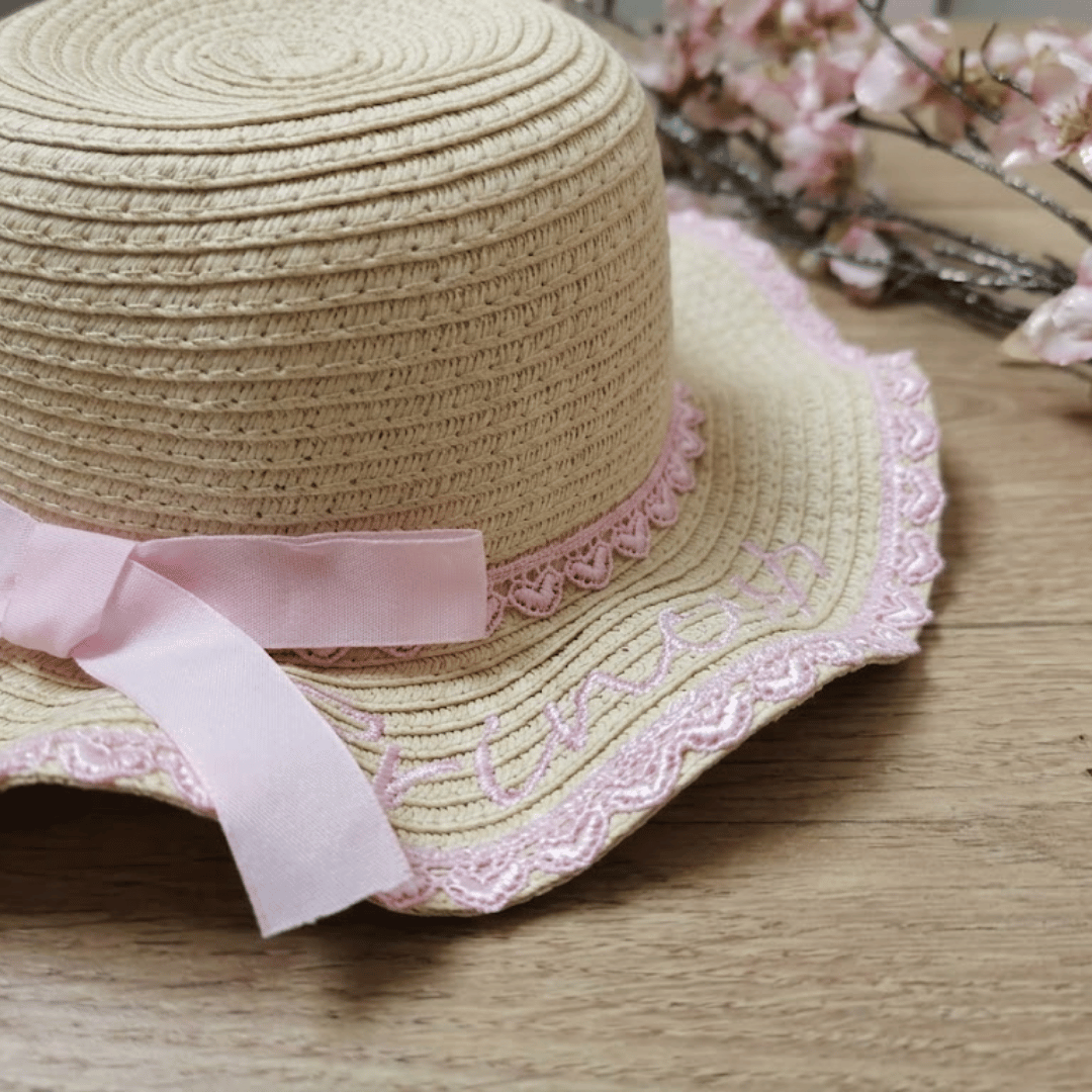 Straw hat with pink lace and ribbon on a wooden surface