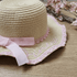 Straw hat with pink lace and ribbon on a wooden surface