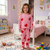 Child wearing pink heart-patterned pajamas in a colorful bedroom.